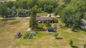 Une grande maison avec un vaste jardin, un petit abri de jardin et un espace potager.