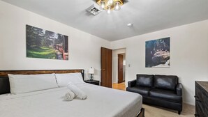 Une chambre d’hôtel avec un grand lit, un canapé en cuir noir et deux tableaux accrochés au mur.