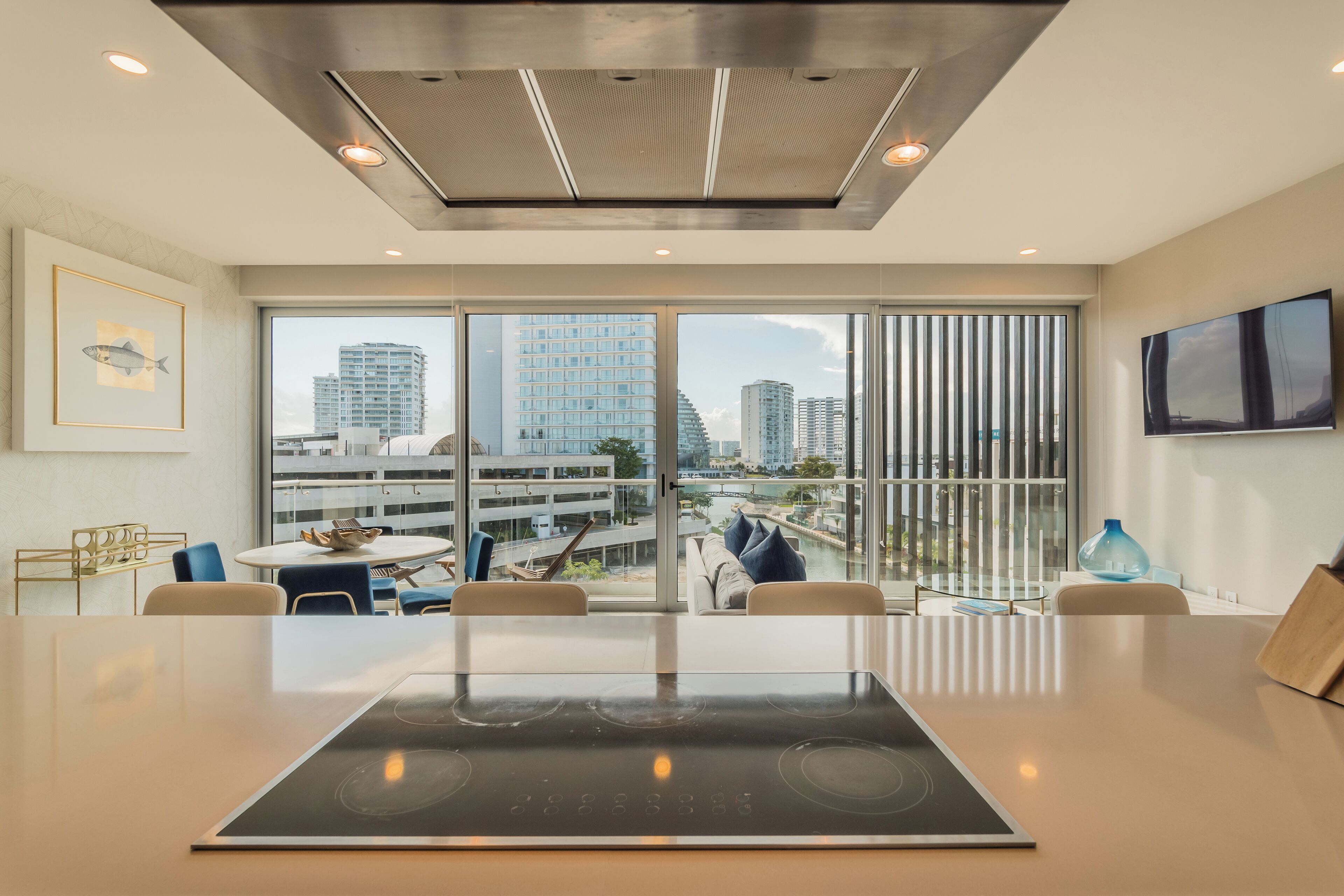 A modern kitchen with a large island, a dining area with a view of the city, and a large window with a view of the cityscape.