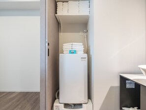 Een boiler met een handdoekhouder erboven, een stopcontact en een bedieningspaneel.