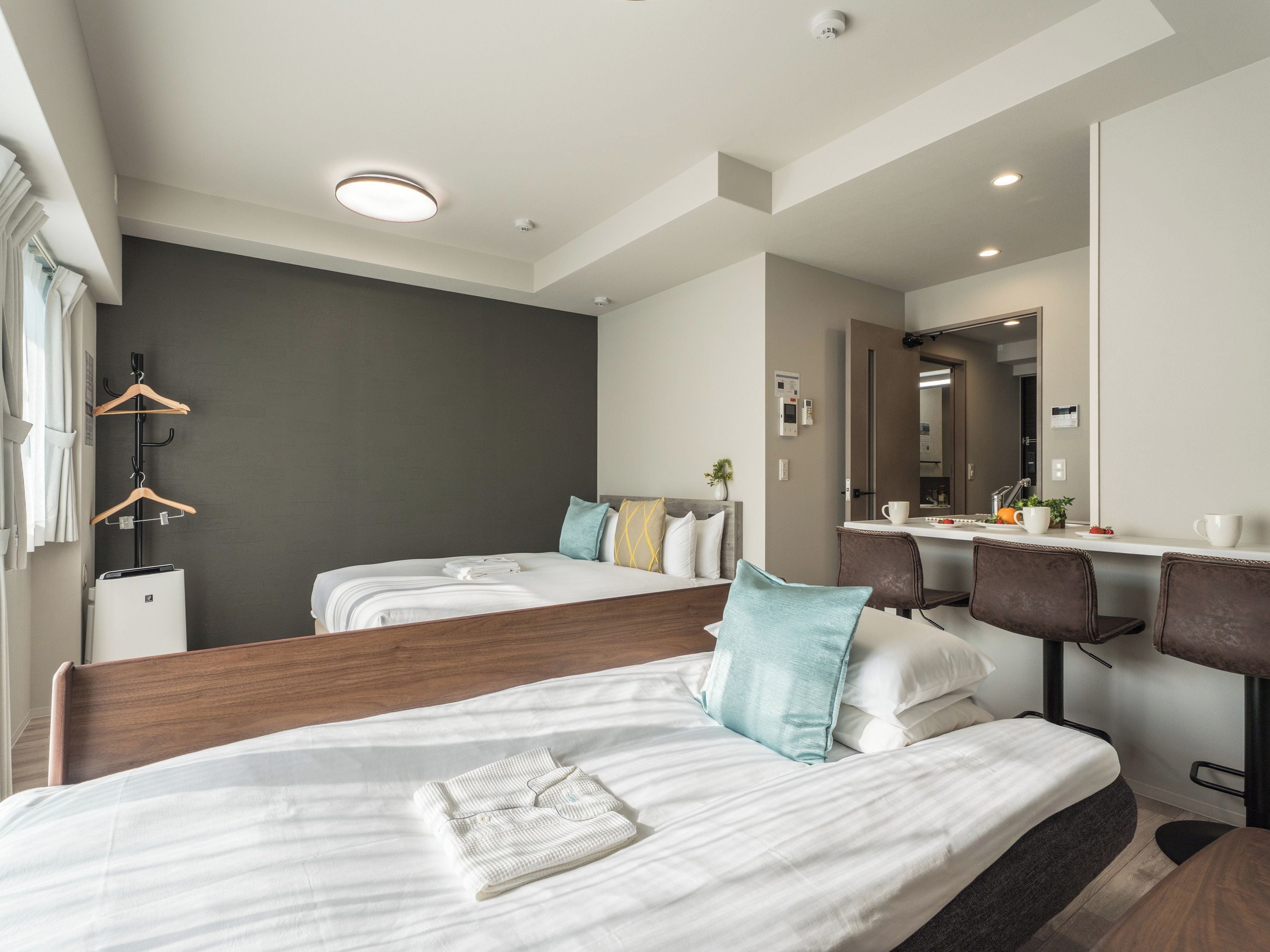A hotel room with two beds, a desk, and a mirror.