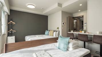 A hotel room with two beds, a desk, and a mirror.