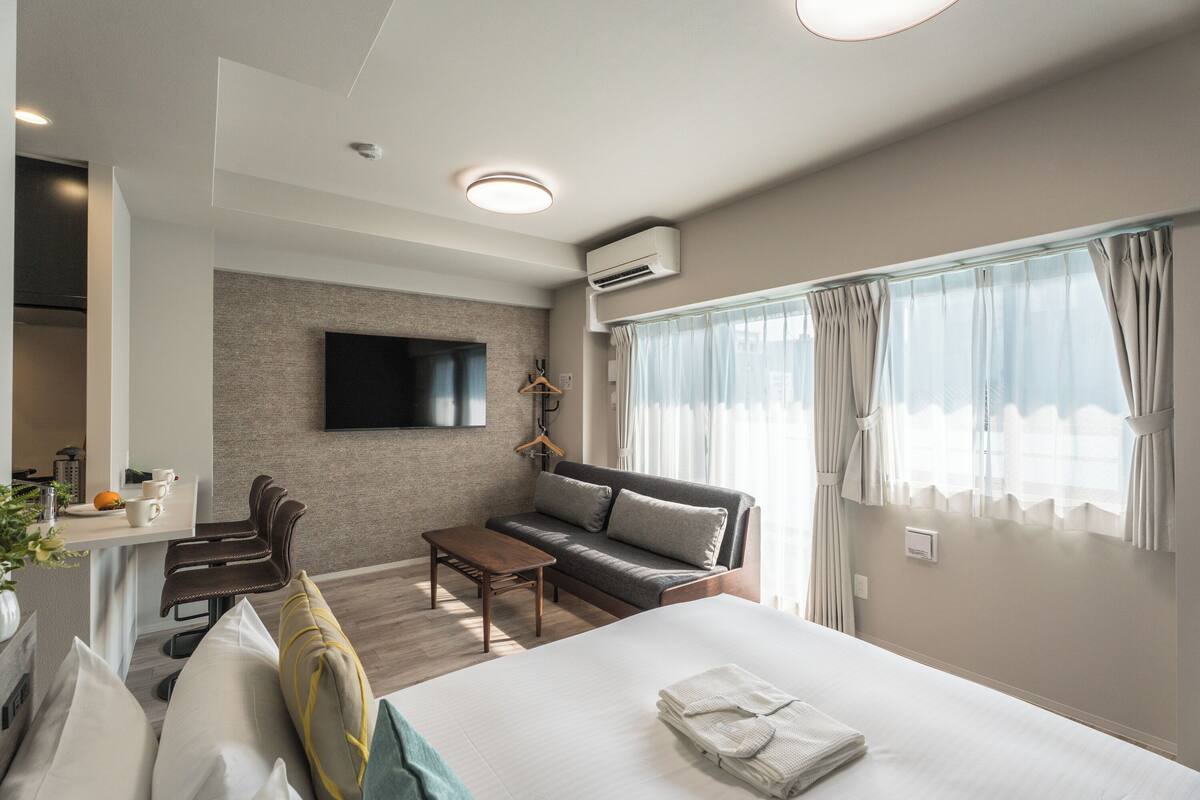 A modern hotel room with a bed, sofa, and desk.