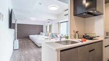 A modern hotel room with a large bed, a kitchenette, and a bathroom.