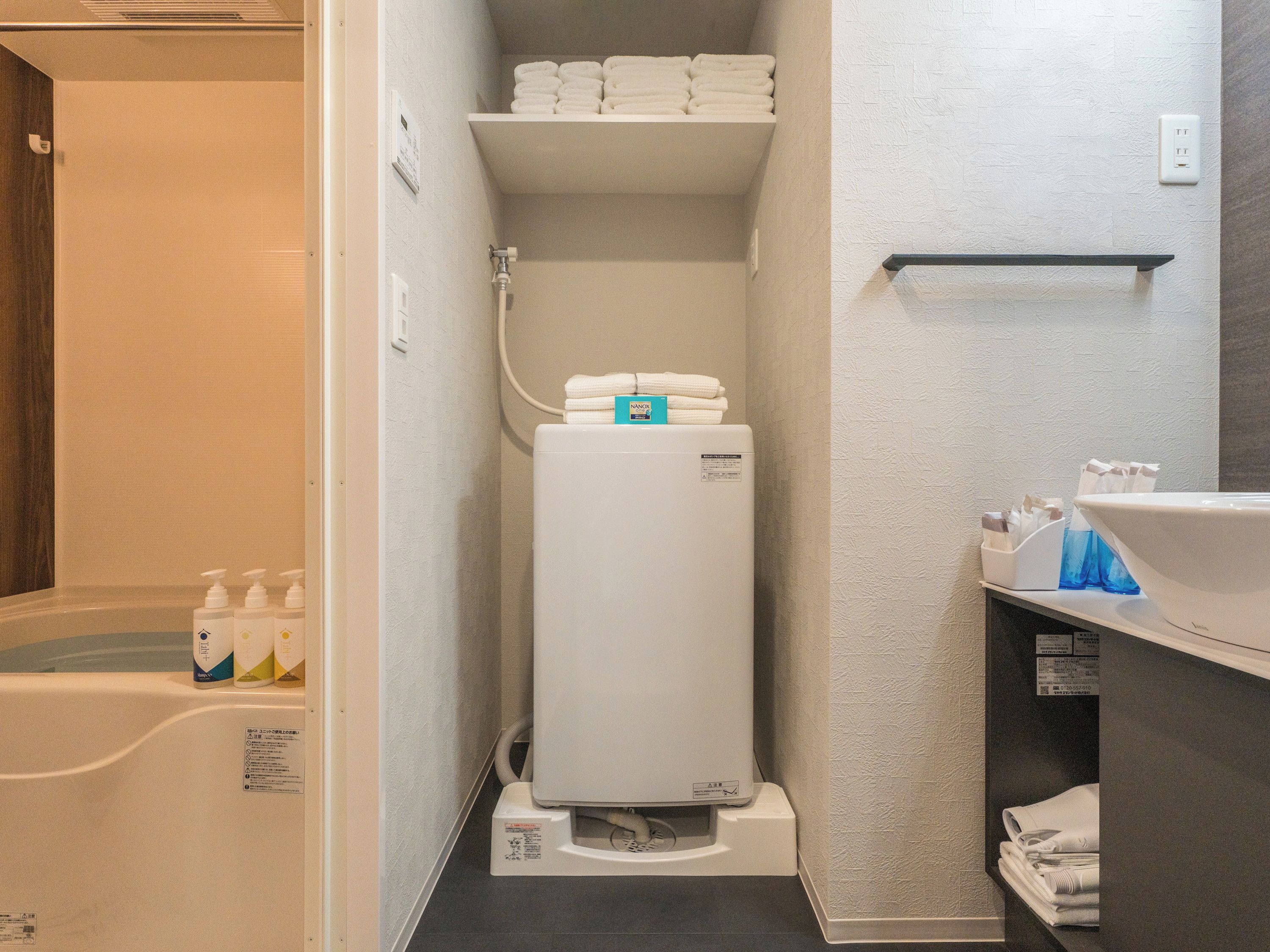 Une petite salle de bain équipée d’un radiateur intégré, d’une étagère avec des serviettes pliées et d’un lavabo avec des articles de toilette.