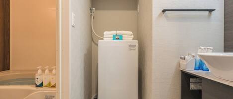 Une petite salle de bain équipée d’un radiateur intégré, d’une étagère avec des serviettes pliées et d’un lavabo avec des articles de toilette.