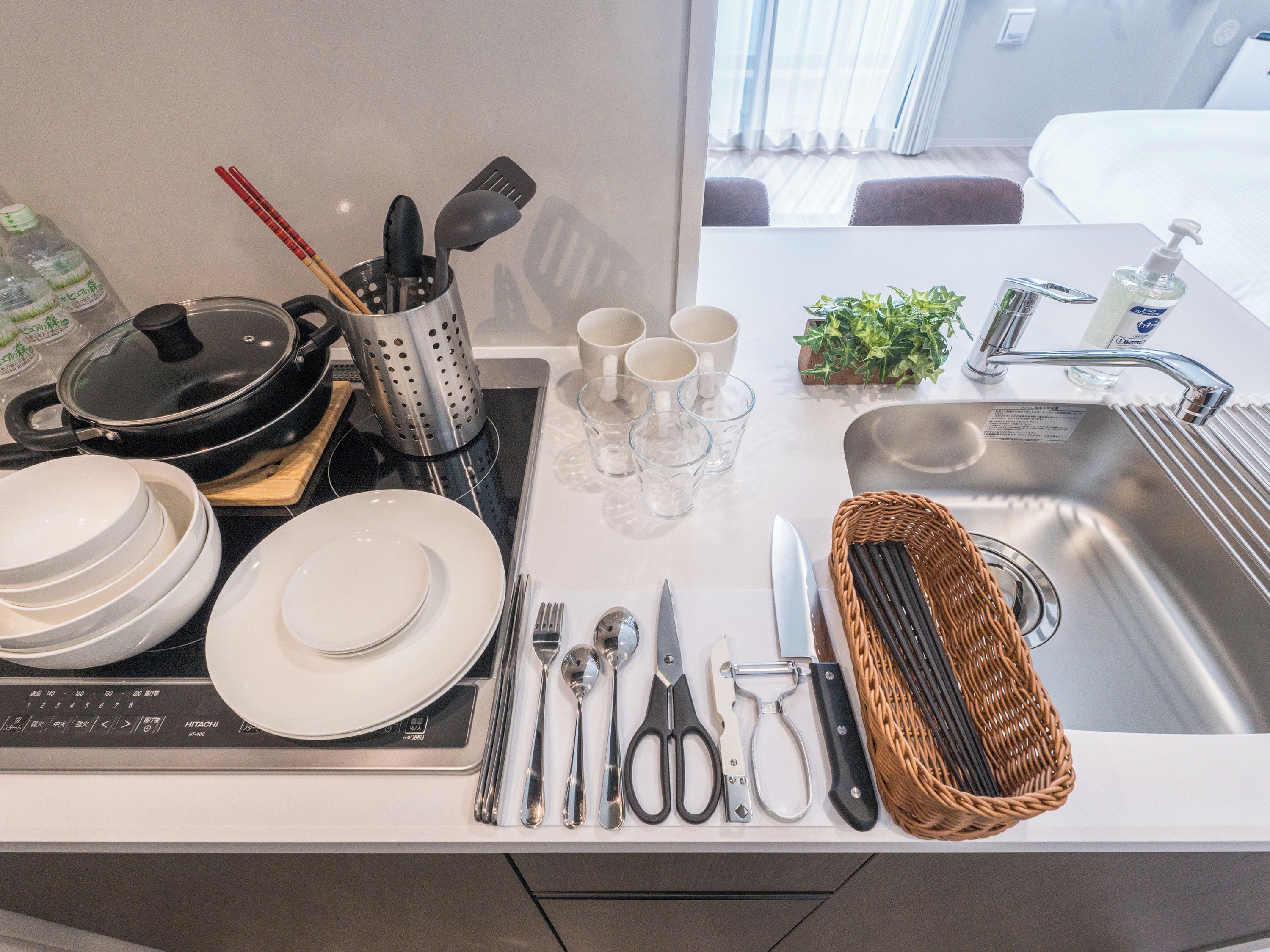 A kitchen counter with various utensils, plates, and a sink.
