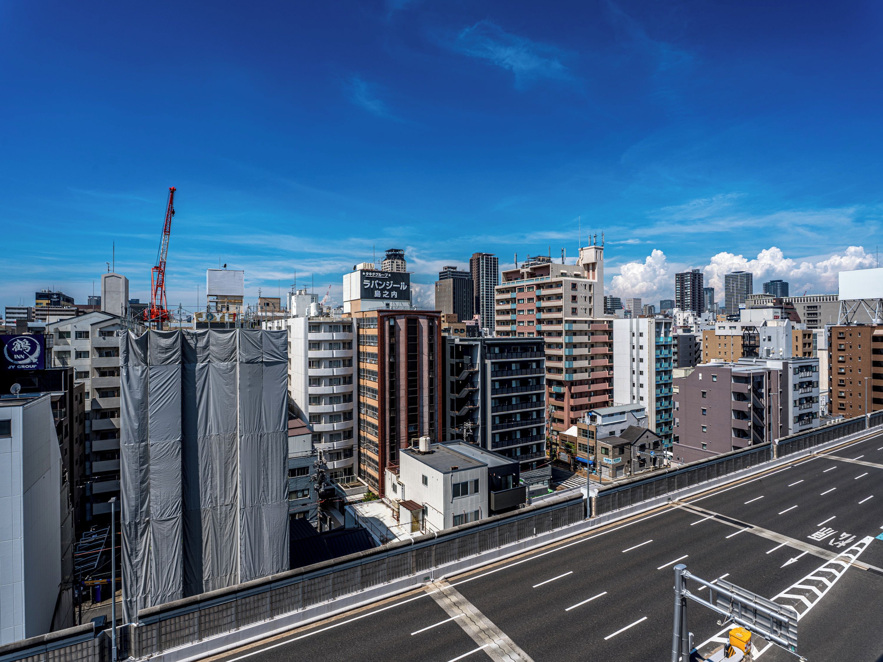 Une vue urbaine avec des bâtiments modernes, une grue de construction et un ciel dégagé.