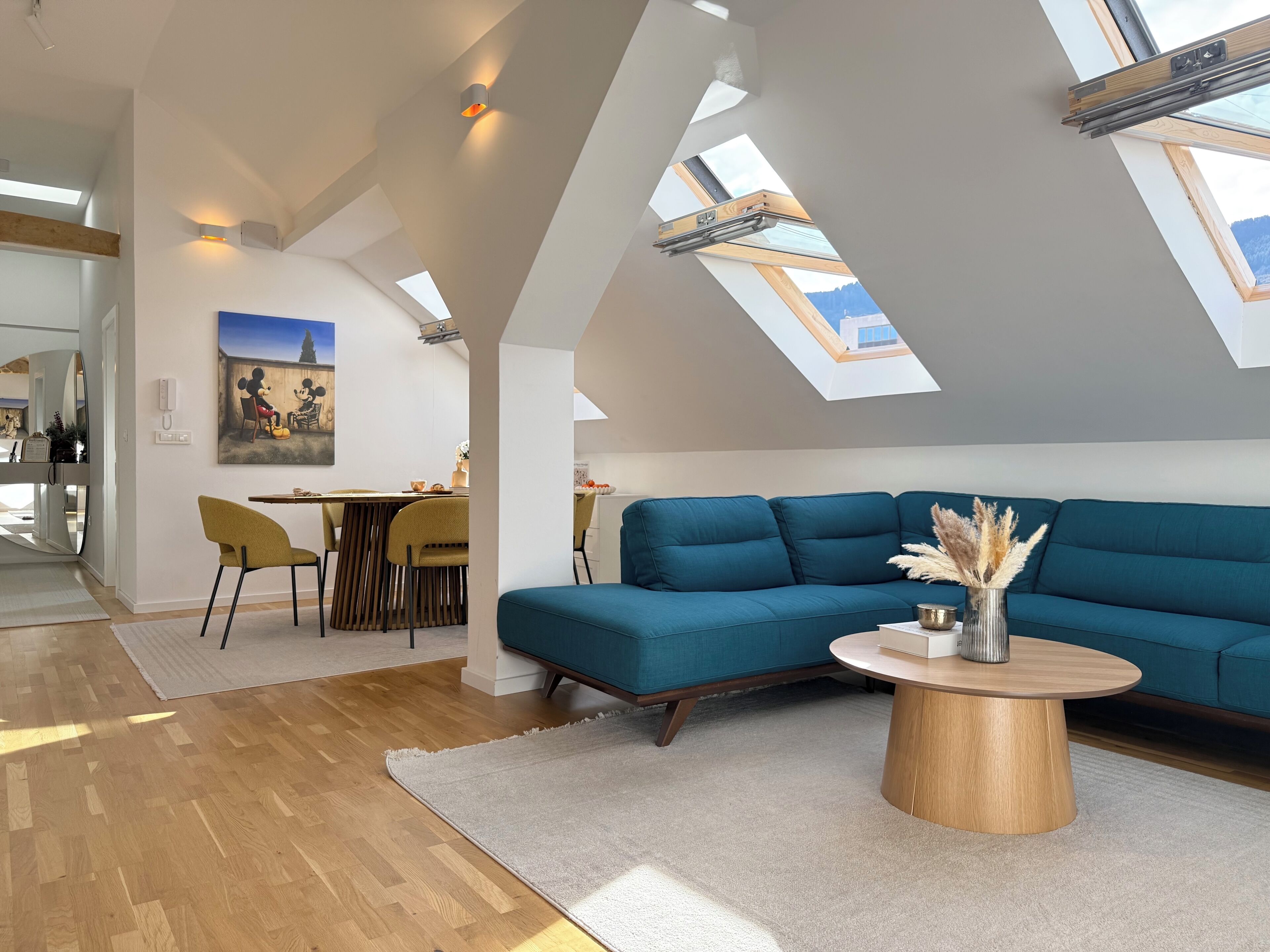 A modern living room with a blue sofa, a wooden coffee table, and skylights.
