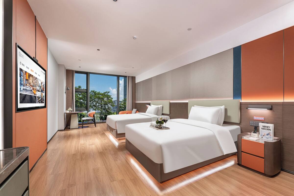 Una habitación de hotel moderna con dos camas, un escritorio y vistas al exterior.
