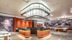 A modern lobby with a curved reception desk, seating area, and a large mural. - From·K Hotel Pazhou (Guangzhou)