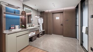 A modern bathroom with a vanity, mirror, towel rack, and a robe hanging on the wall. - From·K Hotel Pazhou (Guangzhou)