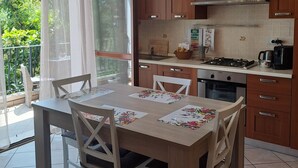 A modern kitchen with wooden cabinets, a gas stove, and a dining area with a table set for four.