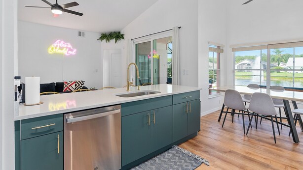Una cocina moderna con lavavajillas, un letrero de neón y un comedor con sillas y una mesa.