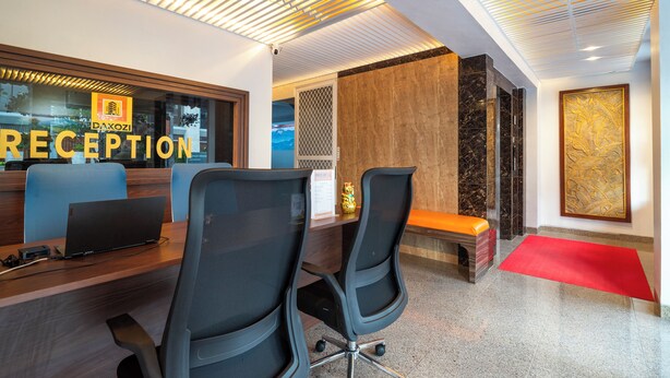 A reception area with a desk, chairs, a laptop, and a red carpet. - Hotel Dakozi Living (Kuta)