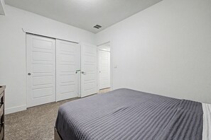 A bedroom with a bed, two white doors, and a carpeted floor. - Stylish Denver 3BR 4BA WFH + Pet-Friendly Yard (Denver)