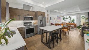 Une cuisine moderne dotée d’un îlot central, d’appareils électroménagers intégrés et d’un coin repas avec un canapé et des chaises.
