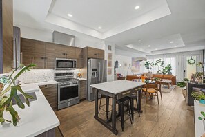 A modern kitchen with a central island, built-in appliances, and a dining area with a sofa and chairs.