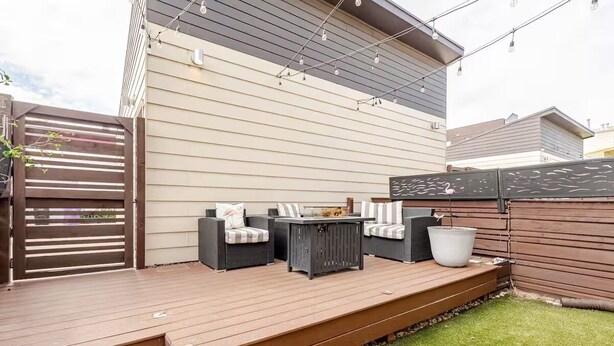 Une terrasse avec des meubles d’extérieur, une plante en pot et une clôture en bois.