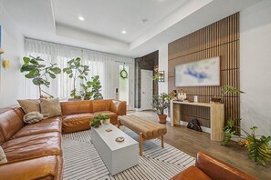 A modern living room with a leather sofa, a white coffee table, and a wooden reception desk. - Stylish Denver 3BR 4BA WFH + Pet-Friendly Yard (Denver)