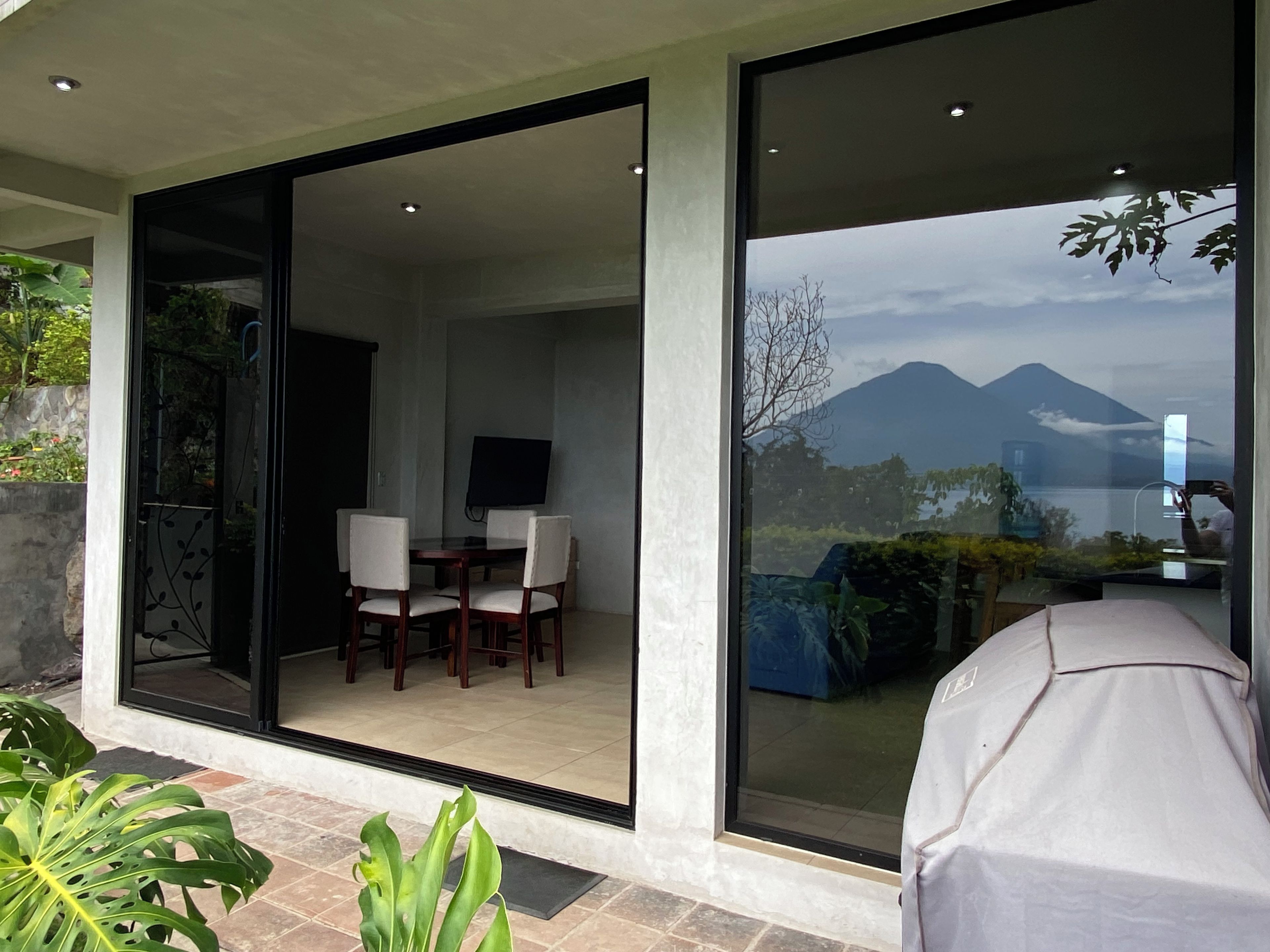 Un interior moderno con comedor, televisor y vistas a montañas a través de amplios ventanales.