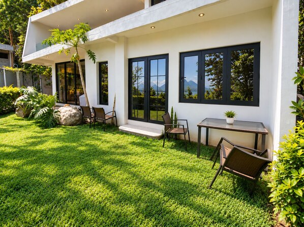 A modern house with a well-maintained lawn, outdoor seating area, and large windows offering views of the surrounding landscape.