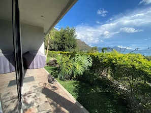 Un balcon donnant sur un jardin luxuriant et sur une chaîne de montagnes lointaine.