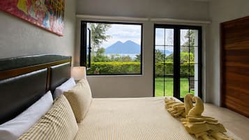 A bedroom with a bed, a window with a view of mountains, and a painting on the wall.