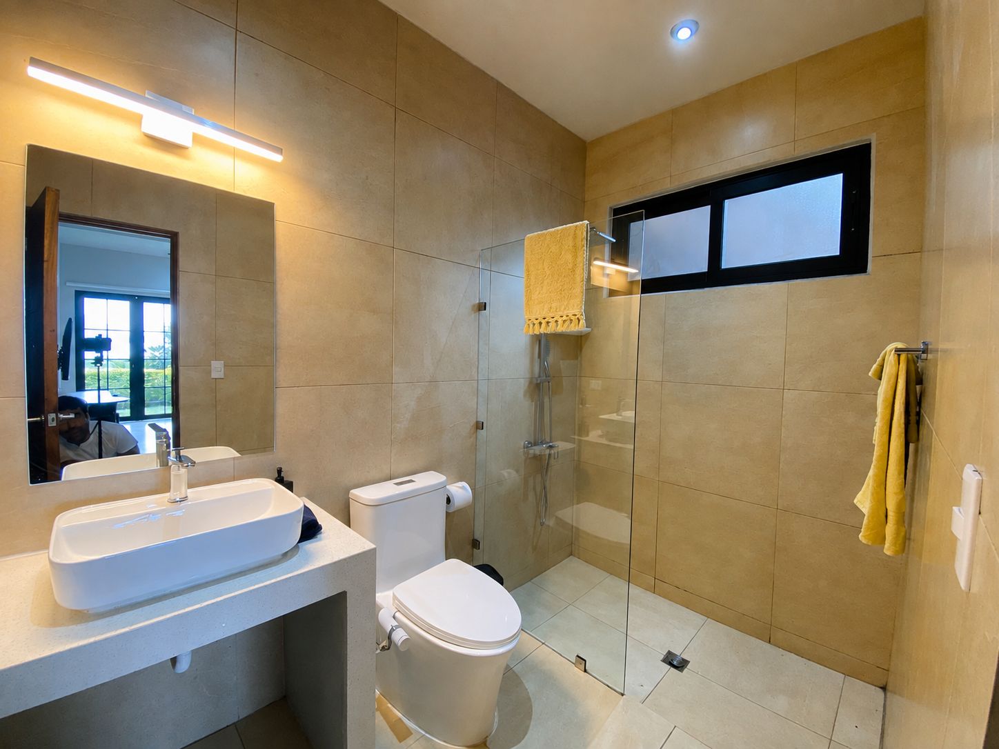 Un baño moderno con cabina de ducha de vidrio, inodoro y lavabo con espejo.