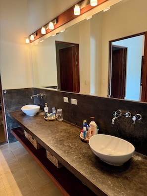 A bathroom with a large mirror, two sinks, and a vanity with toiletries.