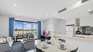 A modern apartment with a dining area, kitchen, and balcony.