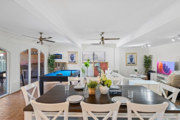 Amplia sala de estar con mesa de billar, mesa de comedor y asientos.