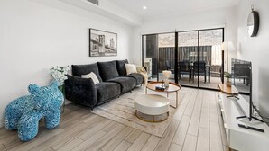 Una sala de estar moderna con un sofá negro, una mesa de centro redonda y vistas a un patio exterior.