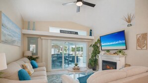 Een woonkamer met een open haard, een televisie en uitzicht op de omgeving.