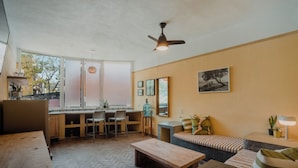 A modern living room with a herringbone floor, a wooden coffee table, a sofa with striped cushions, and a dining area with a kitchen counter and chairs. - Sayula Home (Sayulita)