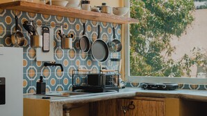 A compact kitchen with a wooden countertop, hanging pots, and a window with a view of greenery. - Sayula Home (Sayulita)