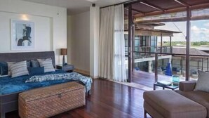 A spacious bedroom with a large bed, a sitting area, and a balcony with a view.