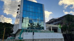 A modern building with a glass facade reflecting the sky and clouds. - CABO BRANCO BEACHFRONT FLAT at the Green Sunset Hotel (João Pessoa)