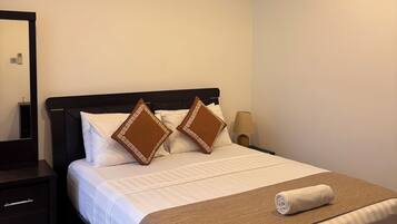 A hotel room with a bed, a nightstand, a lamp, and an air conditioning unit.