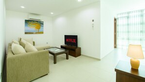 Una sala de estar moderna con un sofá, una mesa de centro, un televisor y una lámpara.