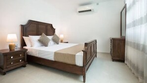 Un dormitorio con una cama de madera, lámparas de noche, una mesita de noche, un armario y un equipo de aire acondicionado.
