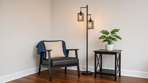 Une pièce avec un fauteuil en cuir noir, un lampadaire et une plante en pot posée sur une petite table.
