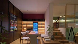 Una cocina moderna con nevera integrada, una zona de comedor con mesa y sillas, y una escalera que lleva a una cocina compartida.