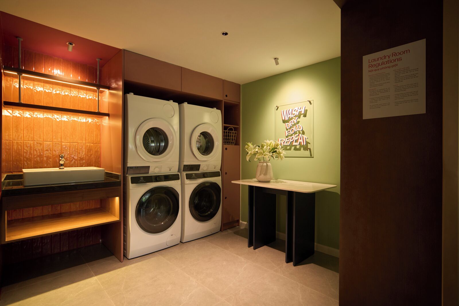 A laundry room with four stacked washing machines, a sink, and a wall-mounted sign with laundry instructions.