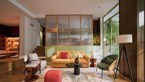 Una sala de estar moderna con sofá, reposapiés, mesa de centro y un amplio ventanal con vistas a zonas verdes.