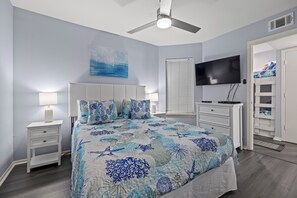 A bedroom with a bed, nightstands, a TV, and a walk-in closet.
