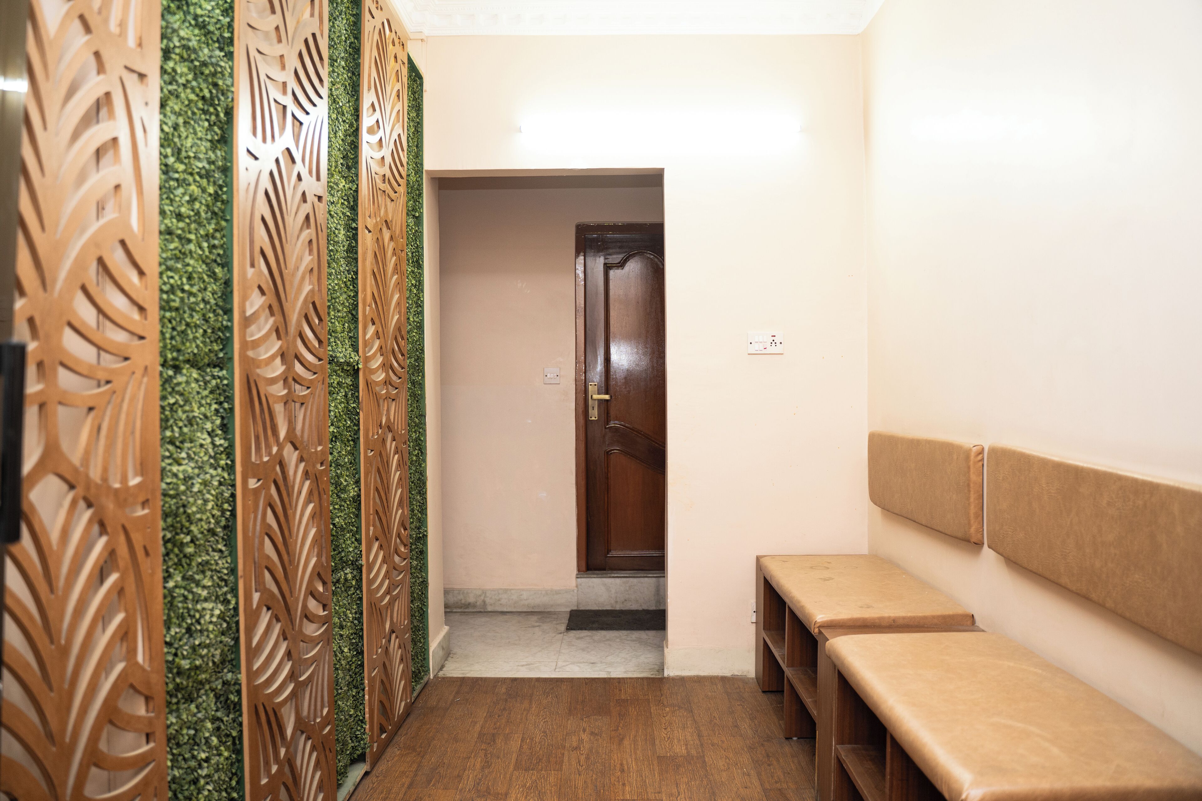 Un corridoio con una panca di legno, una porta e un muro decorato con un motivo a foglia verde.