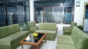 A seating area with green sofas and a wooden coffee table. - Aarya Wellness & Hostel  (Kathmandu)