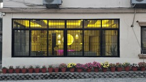 A building with large windows, a row of potted plants in front, and a sign indicating a wellness center inside. - Aarya Wellness & Hostel  (Kathmandu)