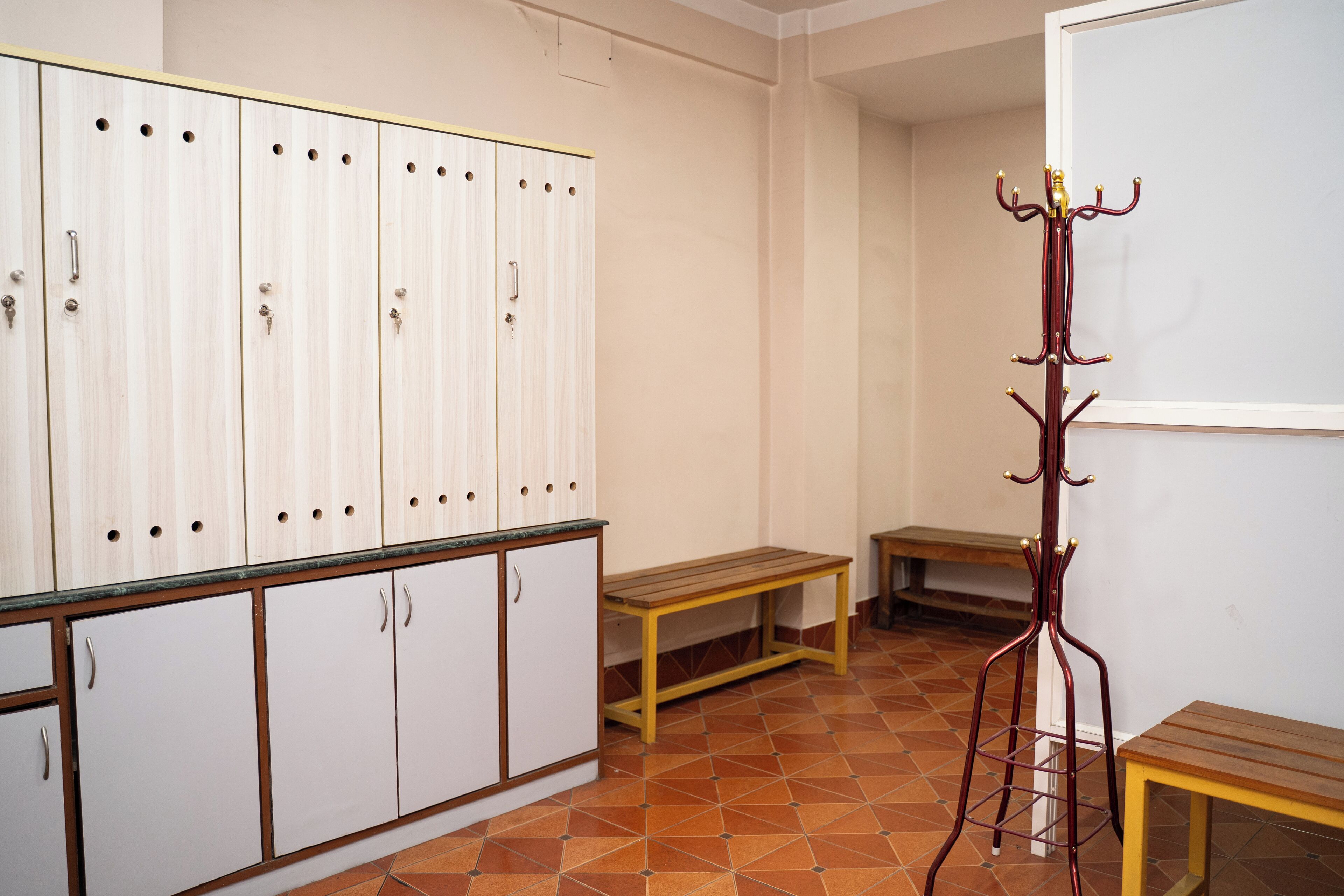 Una habitación con armario, banco y perchero.